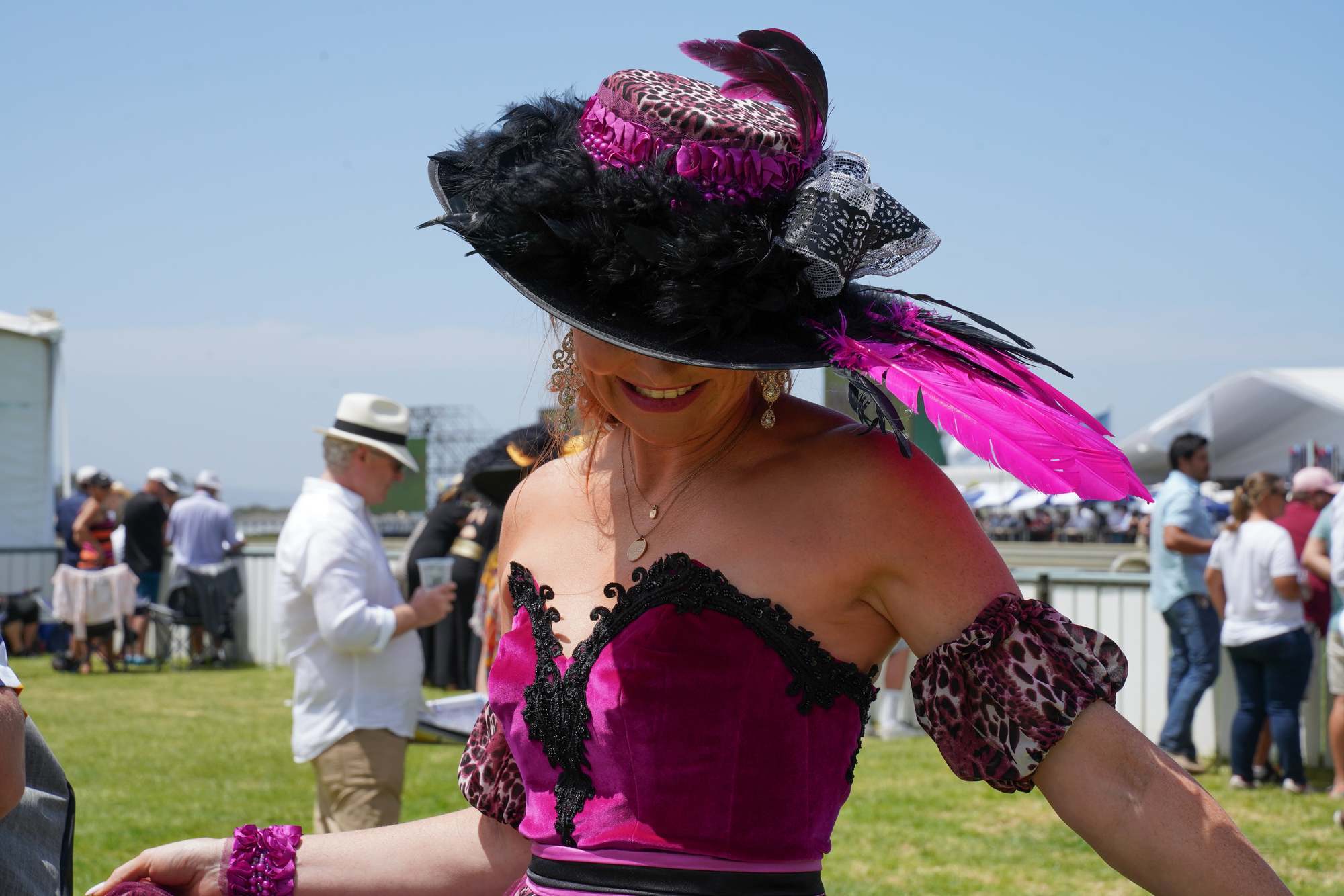 woman at the sun met 2020 with a big, black and pink fascinator kind of hat