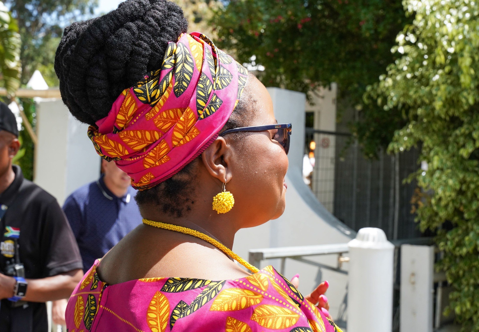 woman with high bun box twists and a colourful headwrap