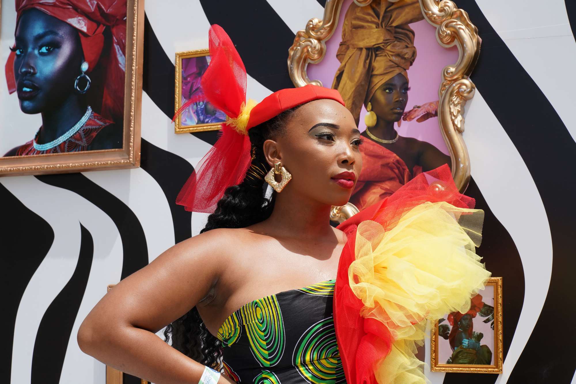 woman at the sun met 2020 with a big red and yellow accessory and slicked back braided ponytail with gold thread
