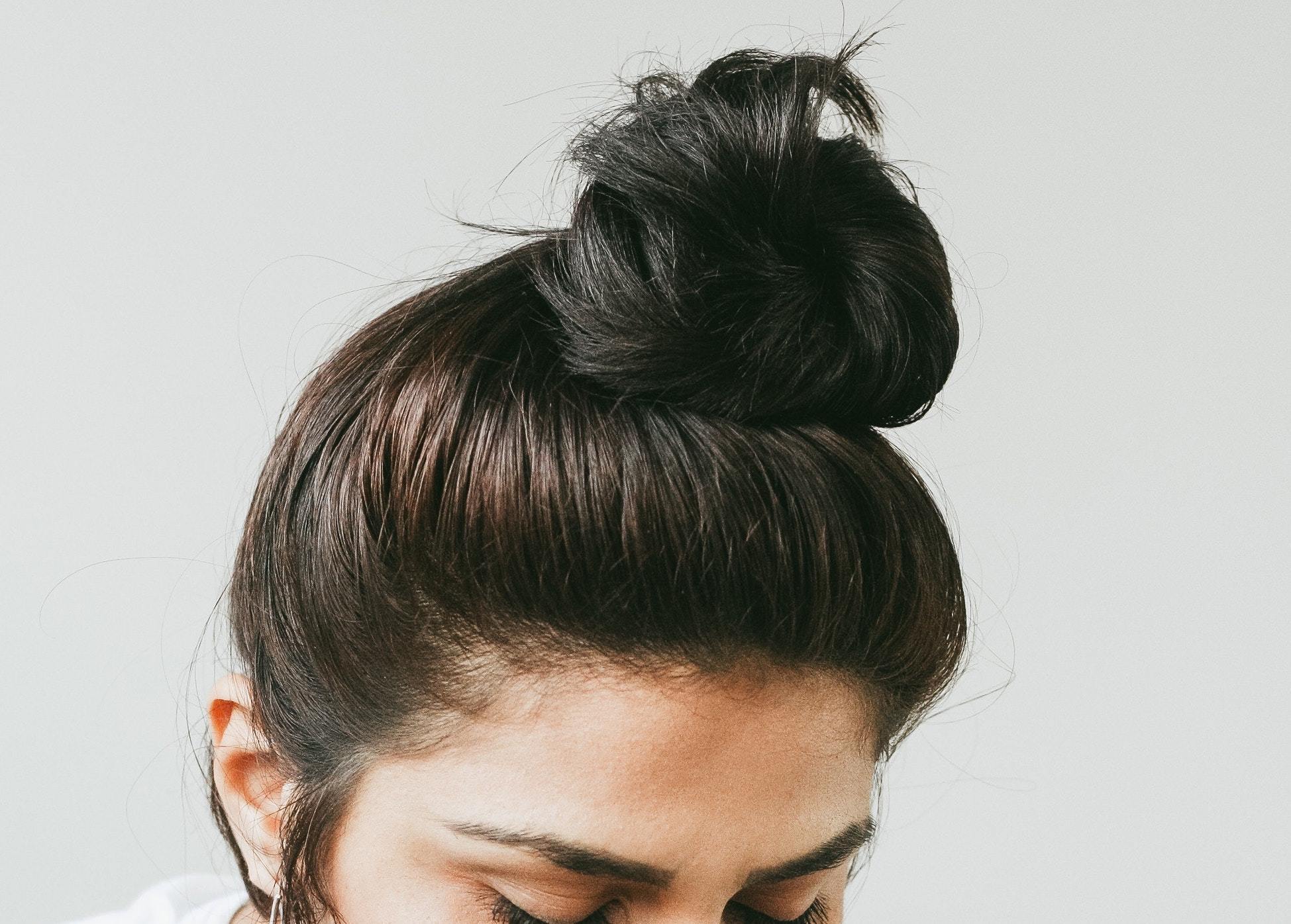 Closeup image of a lady with a top knot hairstyle dark brown hair
