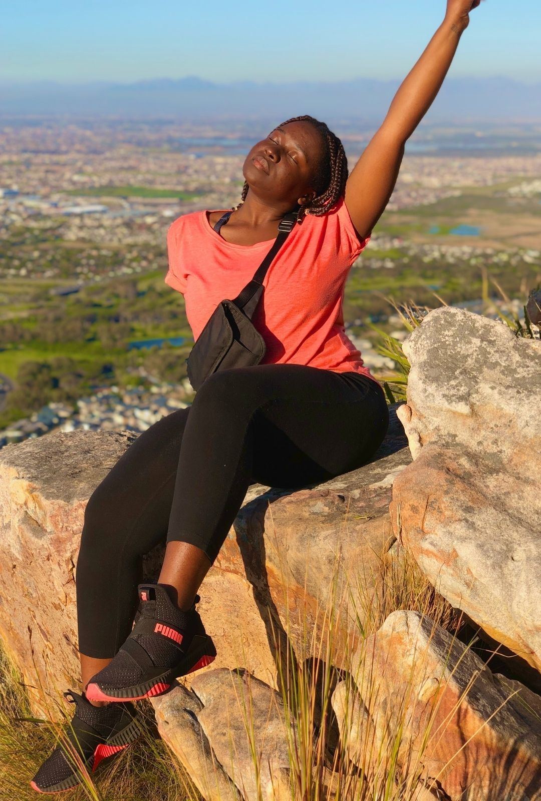woman sitting on a rock wall with her hair tied in braids
