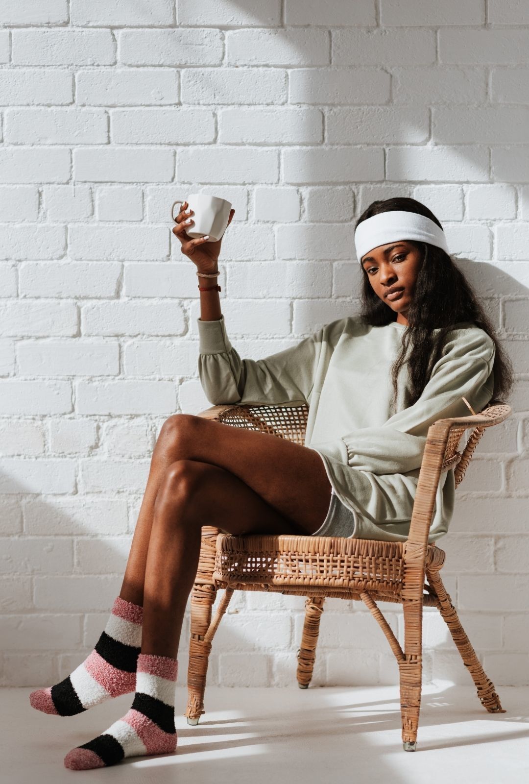 woman sitting down, wearing workout clothes and a wide, white headband