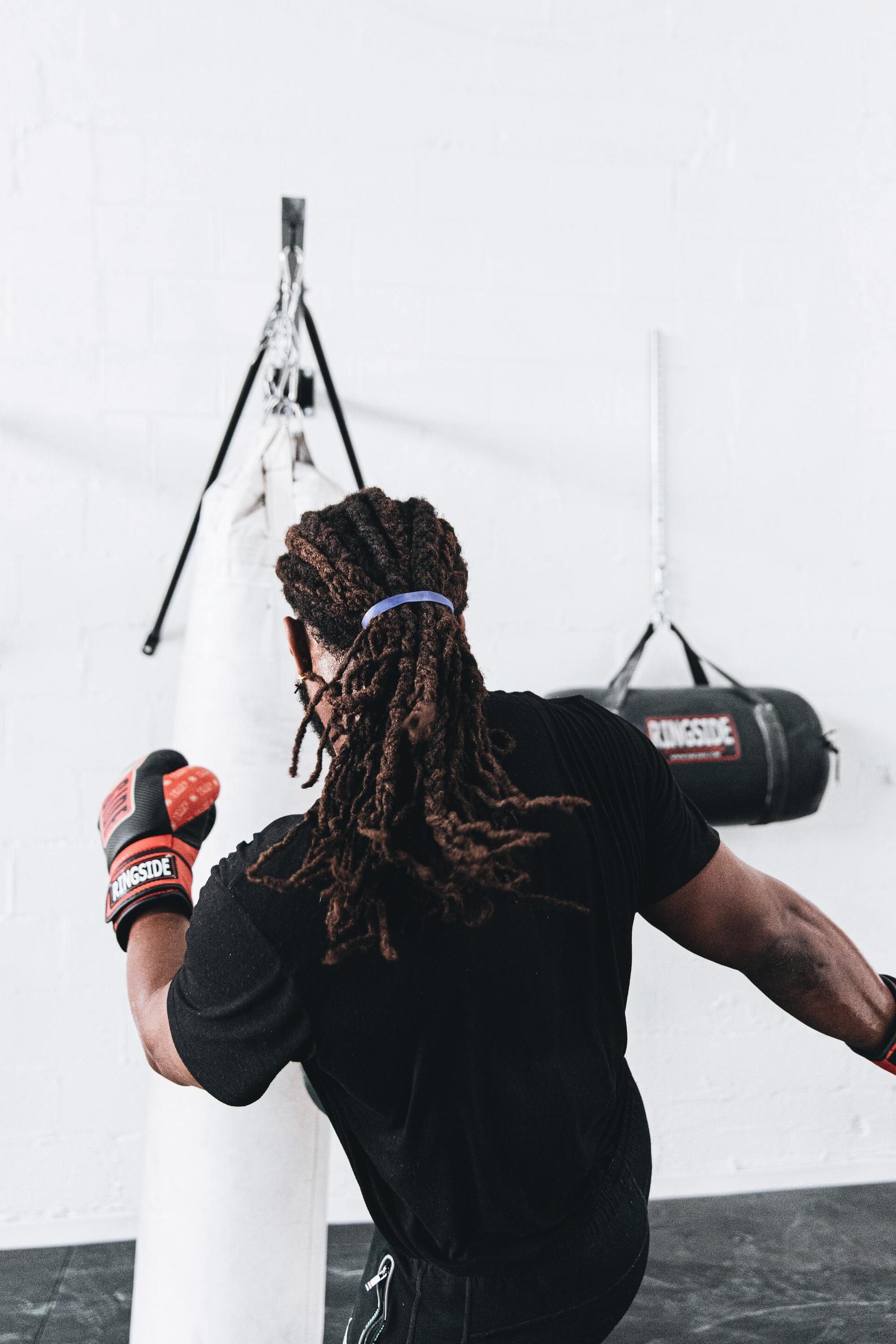 workout hairstyle: man with long locs tied into a ponytail, doing kickboxing
