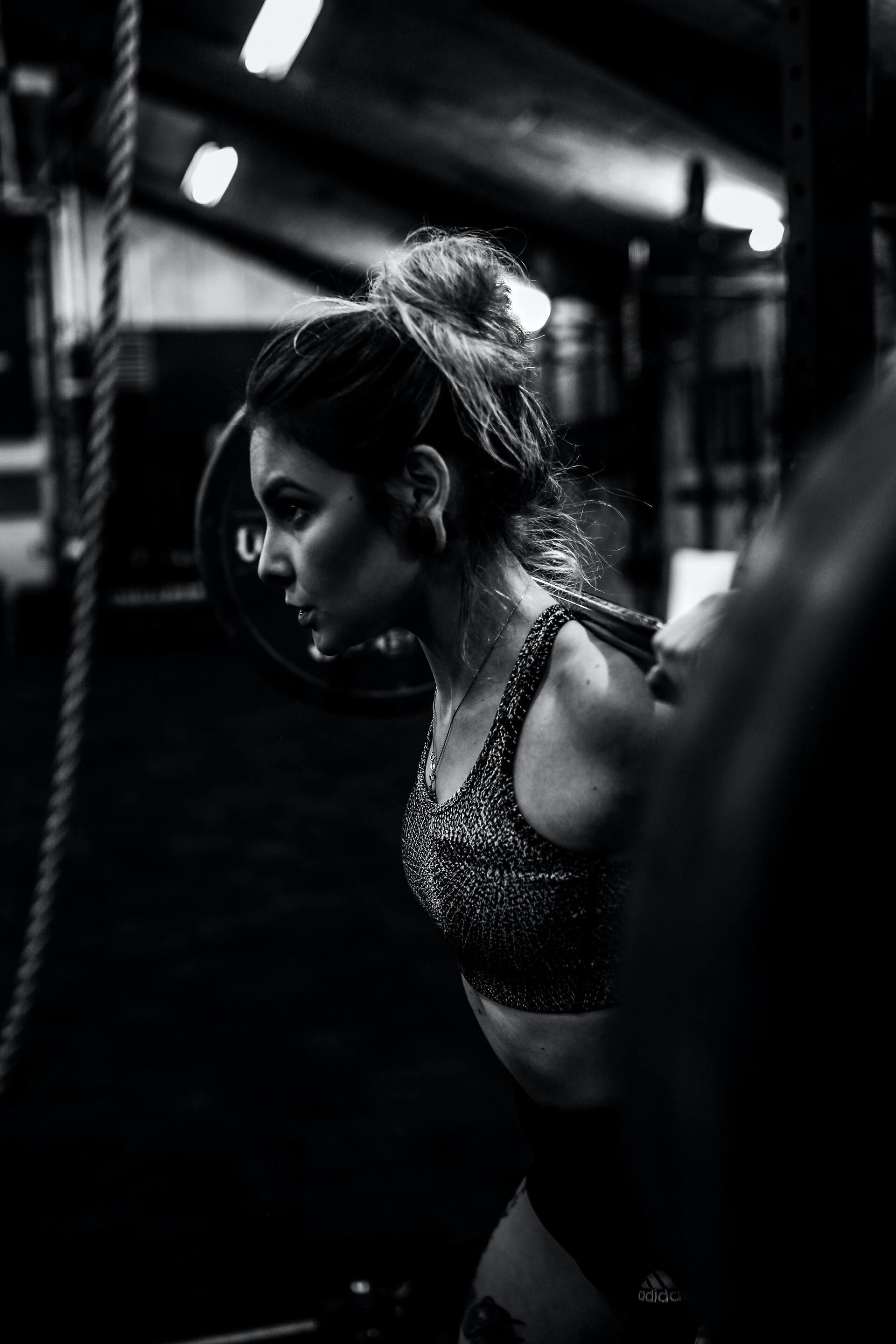 workout hairstyle: woman lifting weights with her hair tied in a messy topknot