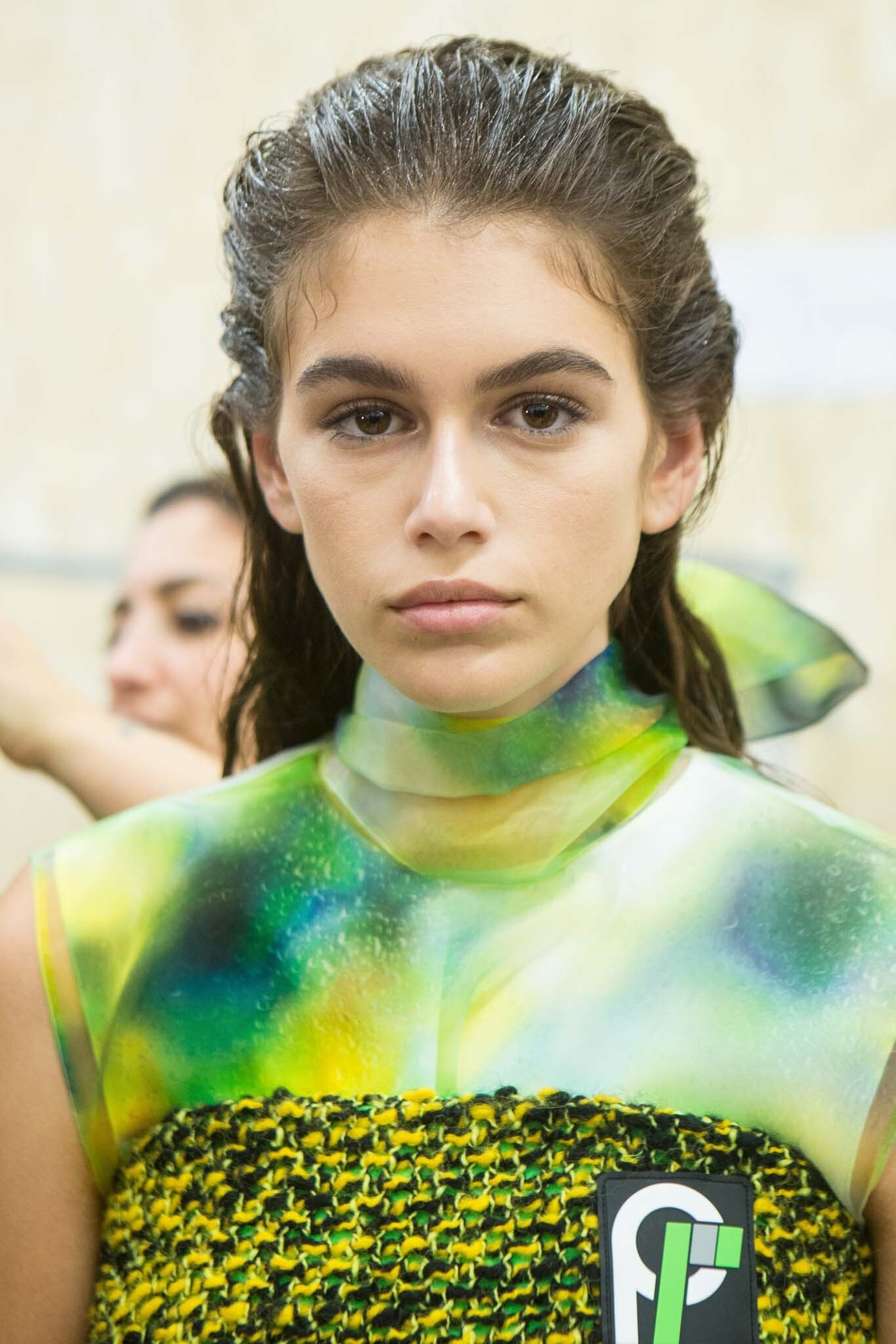 New hairstyle: Kaia Gerber with brown swept back wet look straight hair at Prada FW18. Kaia is wearing a green tie-dye top.