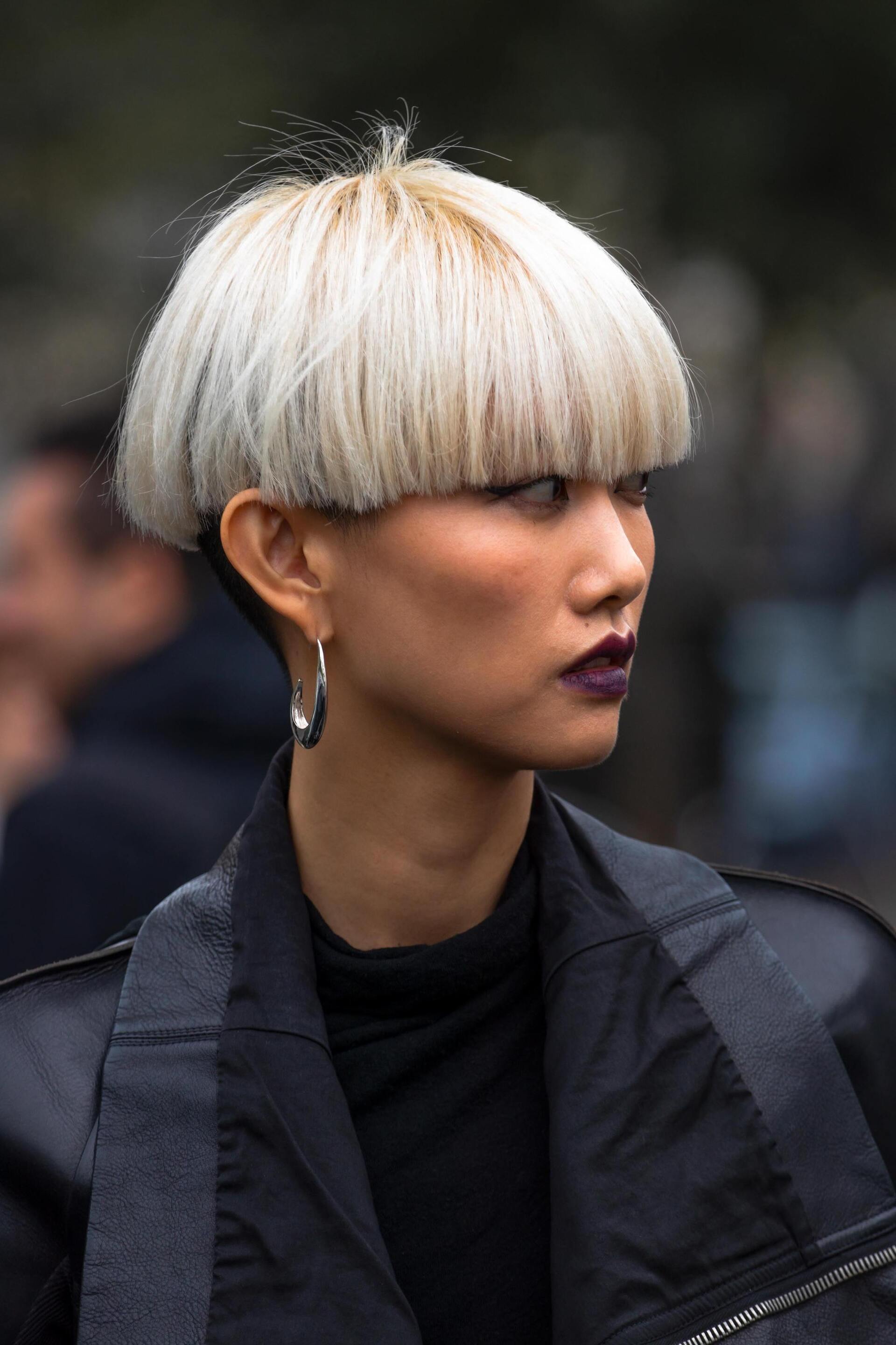 Kpop inspired hairstyle: woman with bowl haircut that covers her eyebrows; hair dyed ash blonde with a black undercut