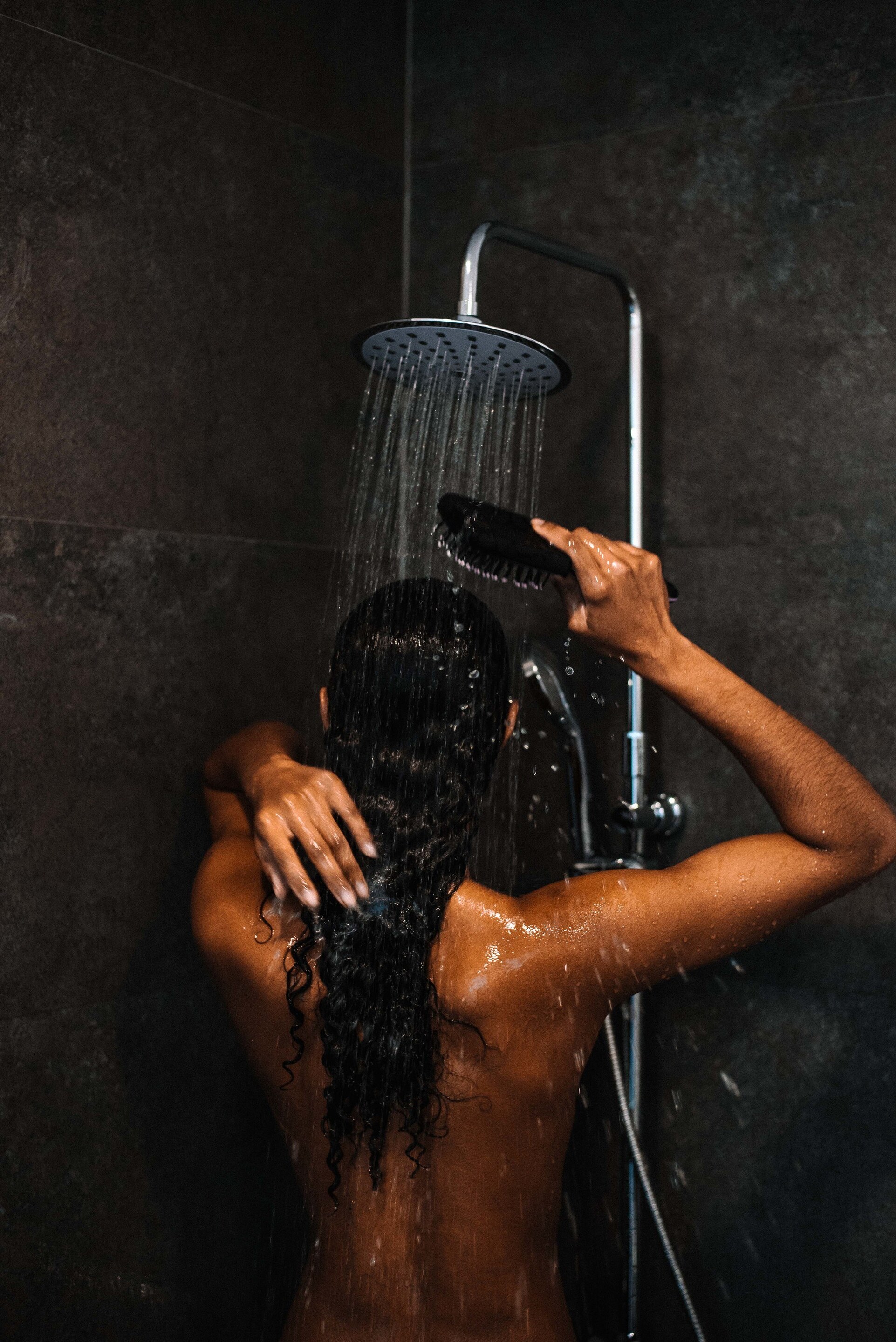 winter flyaways: woman with long brown hair rinsing her hair under the shower