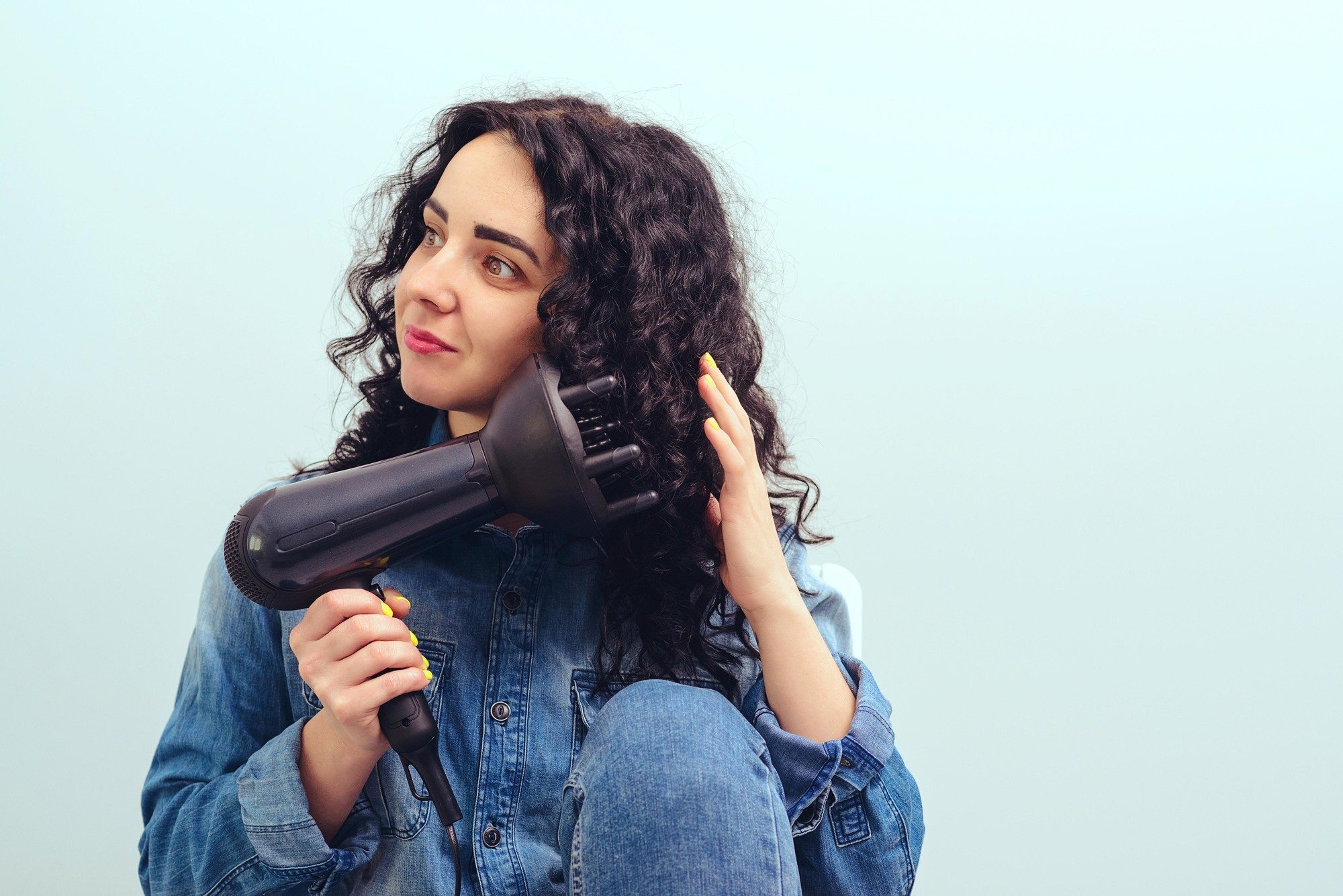 hair dryer attachments: Woman using a hairdryer at home. Beauty and haircare concept. Female drying hair. Girl styling her curly hair with hairdryer with special diffuser nozzle.