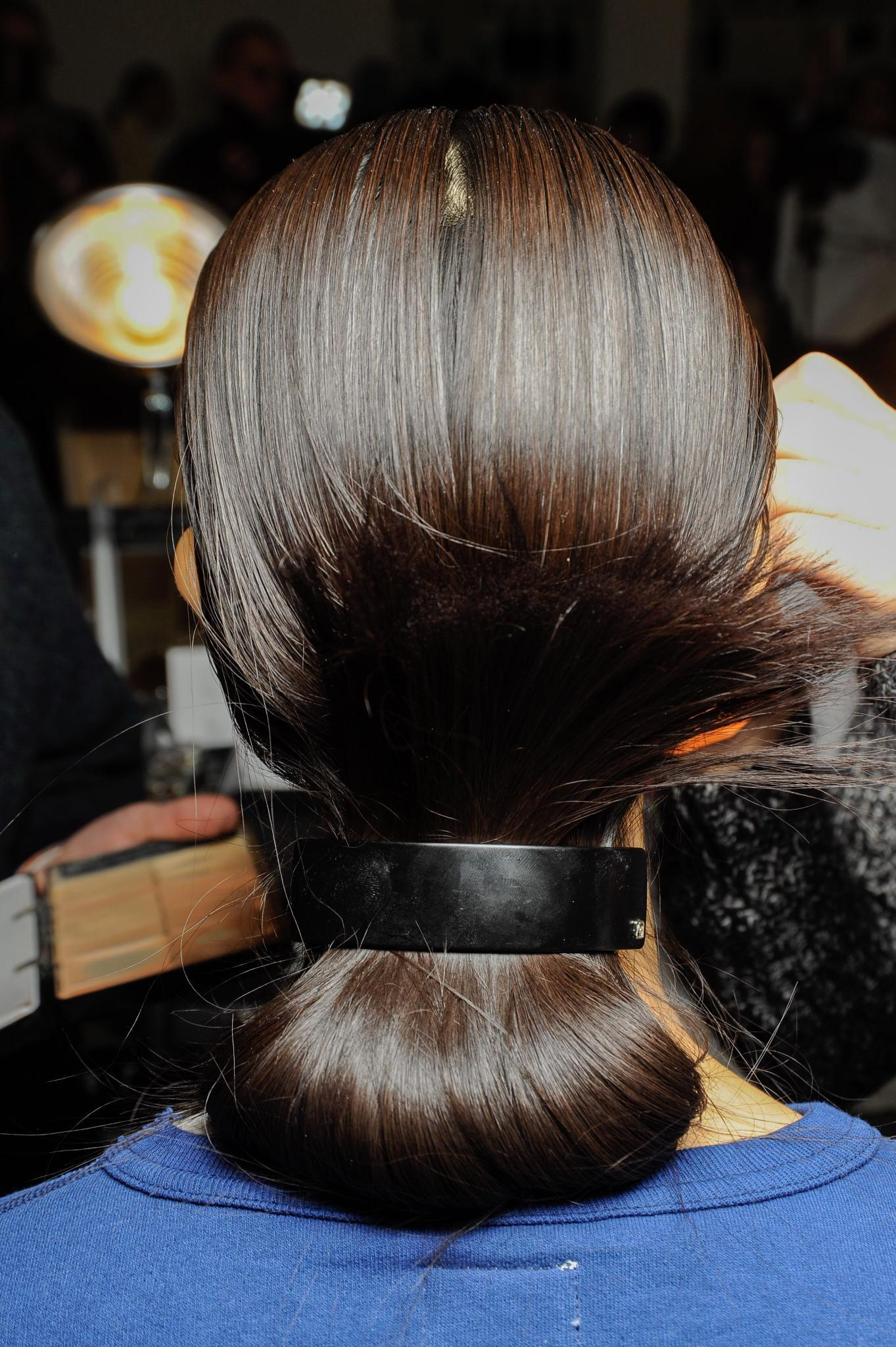 Hairstyles for long hair: Back view of woman with straight brown long hair styled in a low flipped up style secured with a large black barrette accessory at the Suno FW15 runway show.