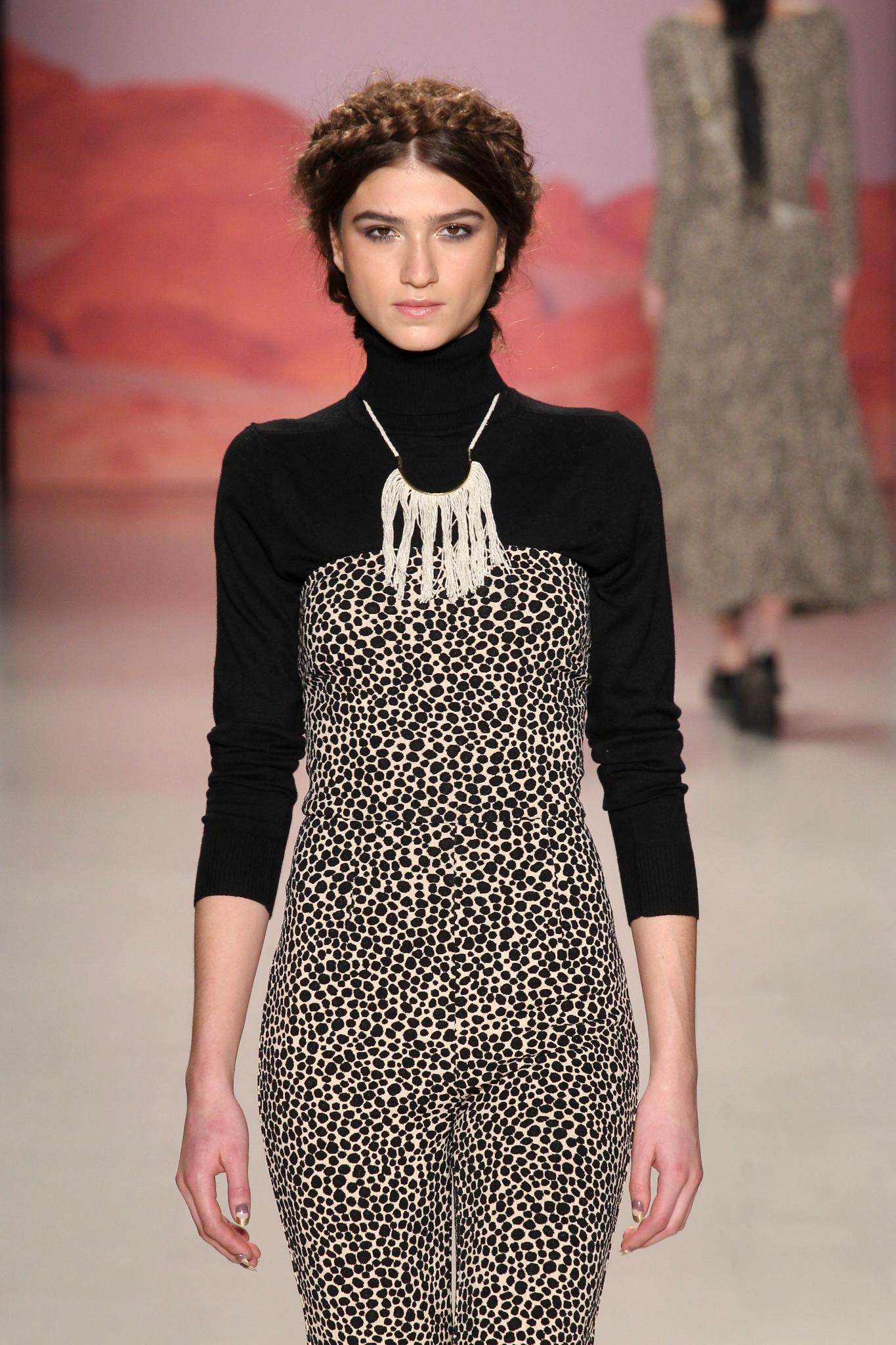 Woman on Mara Hoffman fw15 runway wearing milkmaid braids. Woman is wearing a black long sleeve top with high neck and patterned body with large necklace.