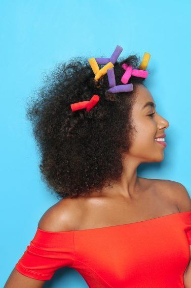 Black woman with curling rods in her afro hair