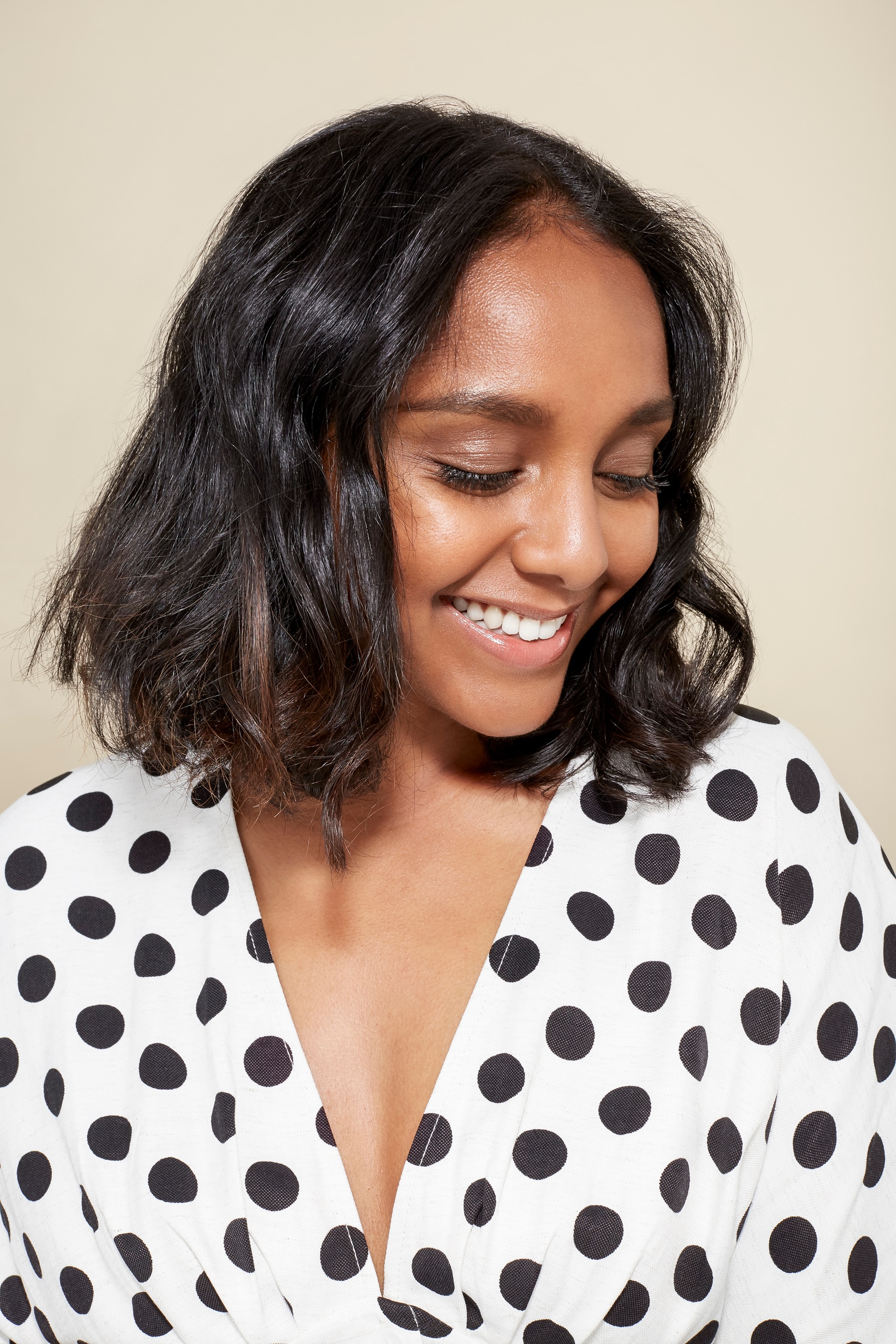 Short hairstyles: Woman with wavy dark brown bob wearing a polka dot blouse top.