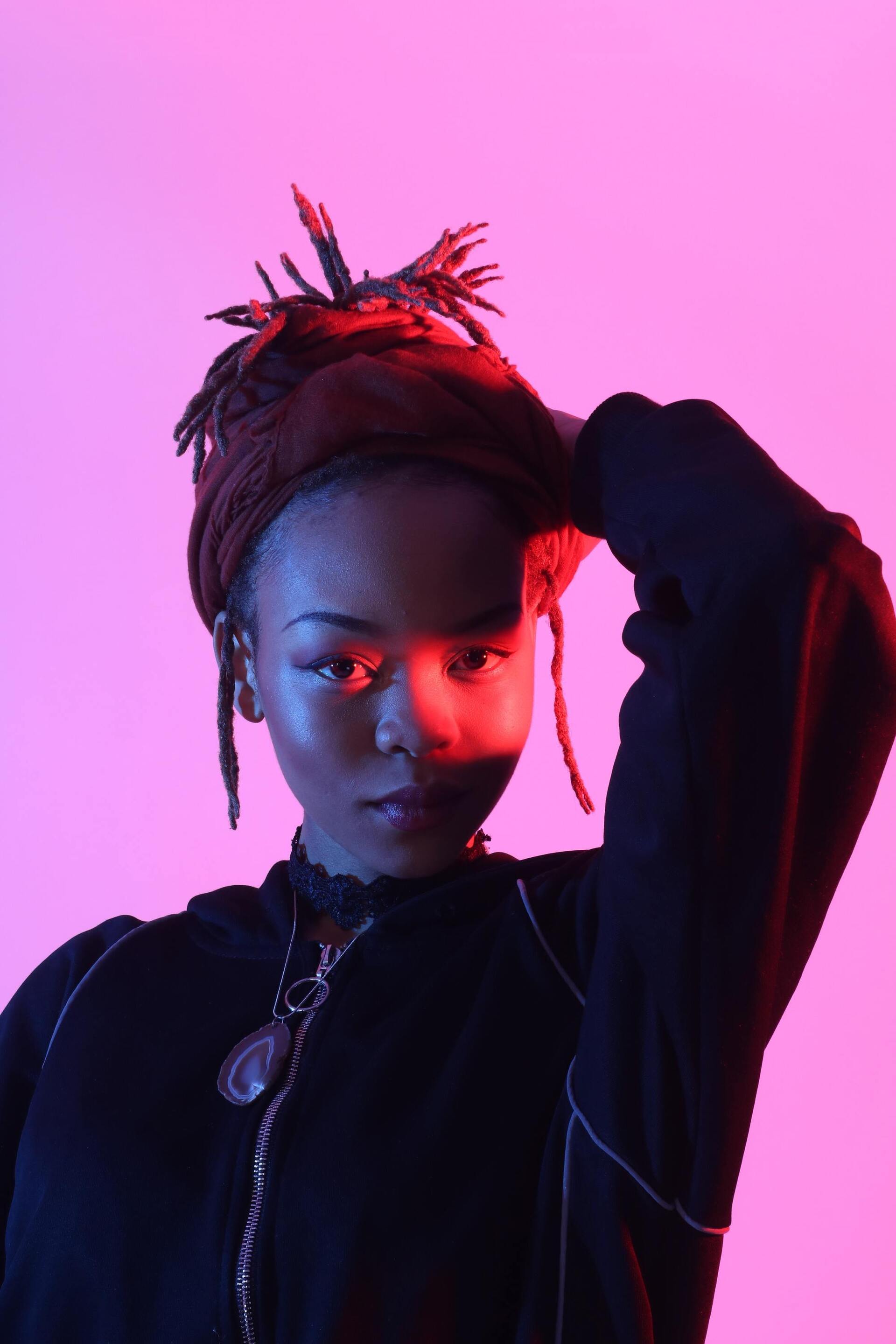 woman with locs tied up into an updo hairstyle with a burgundy headwrap