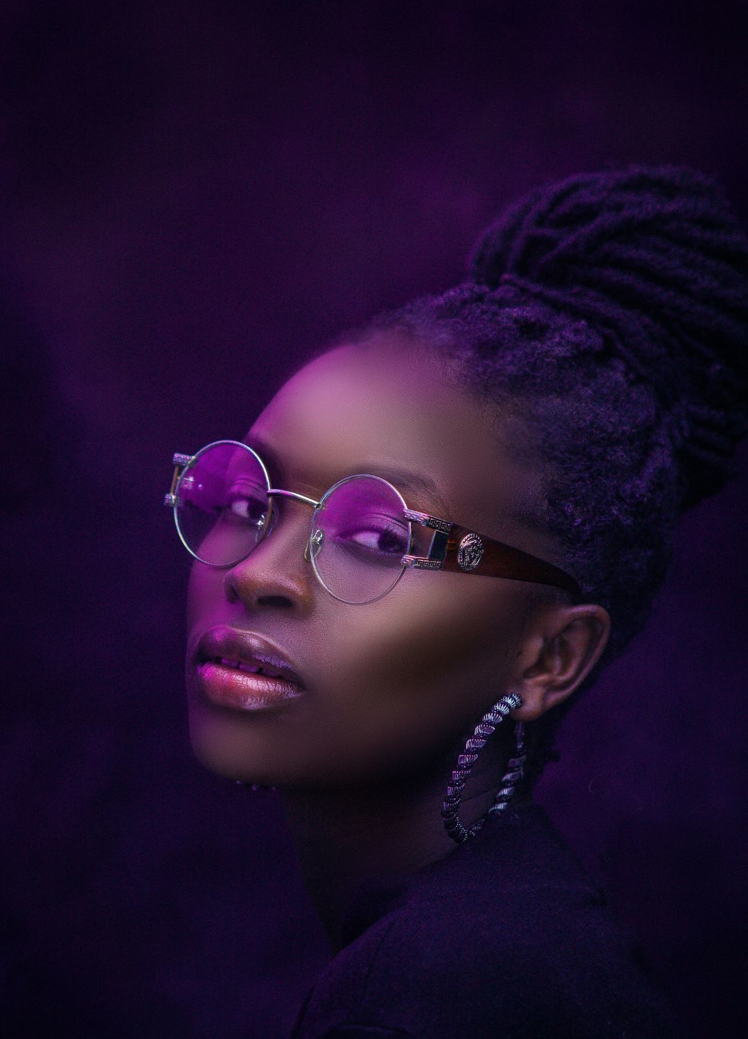 woman with locs tied up into a high bun hairstyle