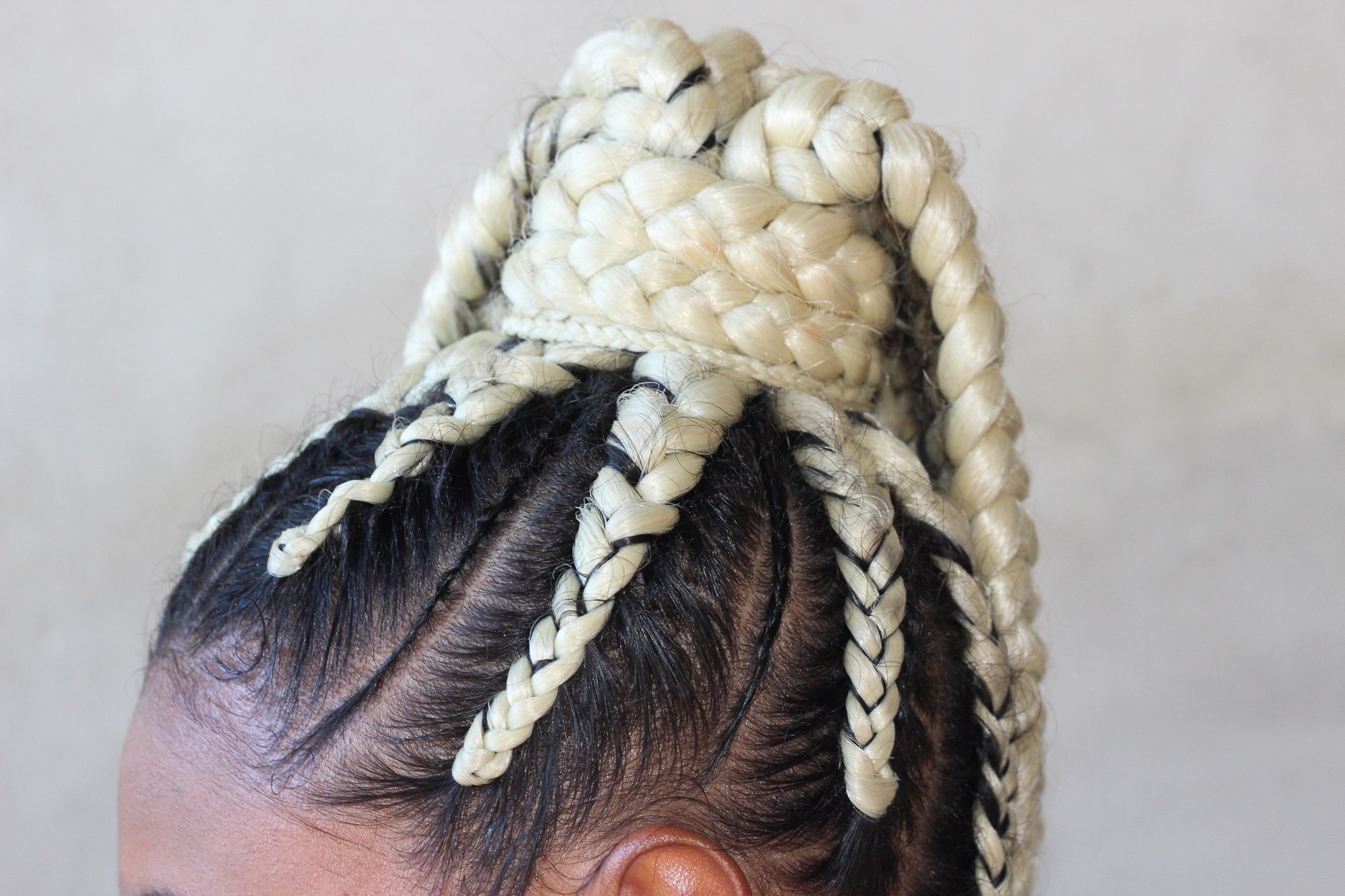 closeup bright blonde and black cornrows ponytail