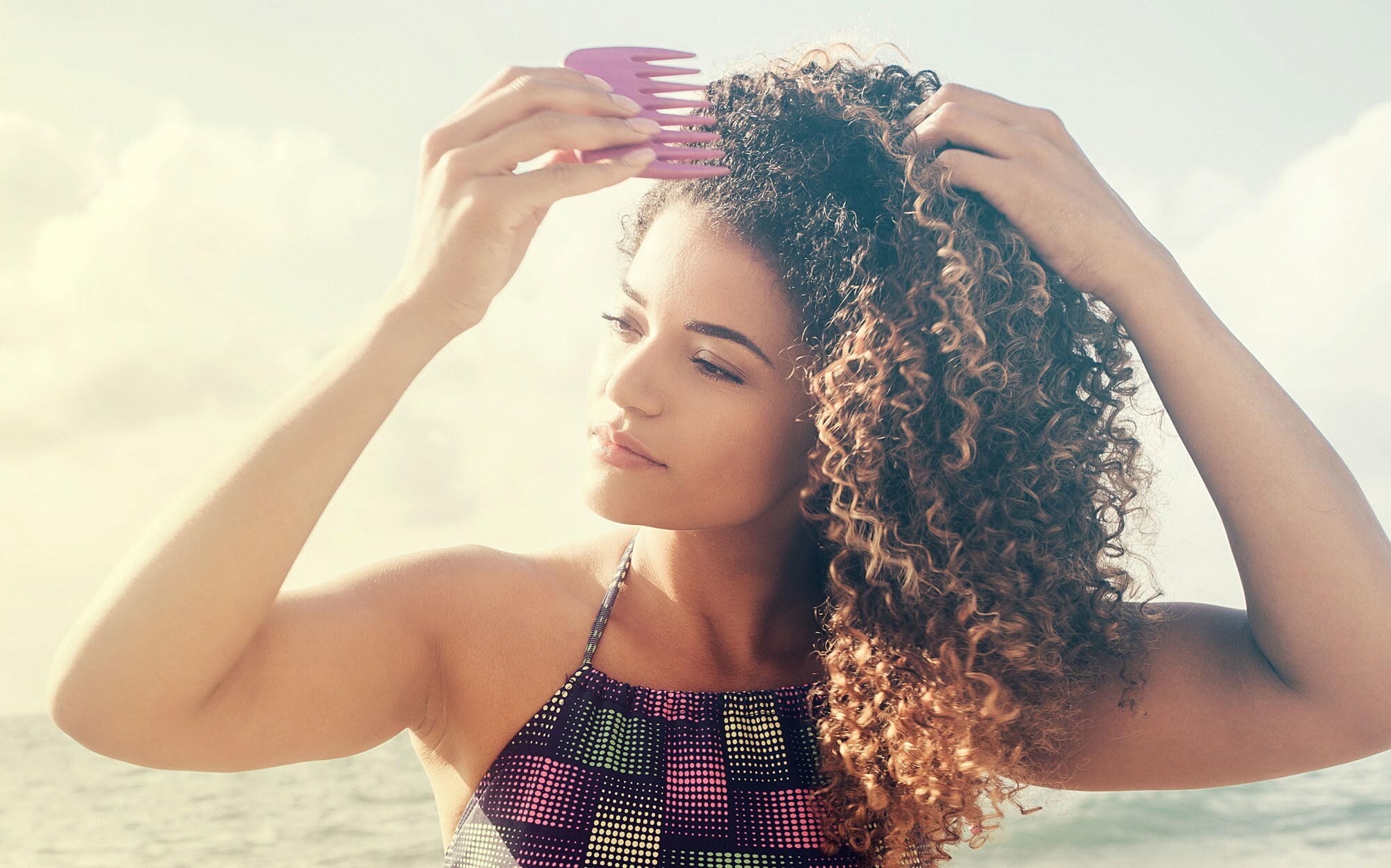 reduce damage: woman detangling her naturally curly hair