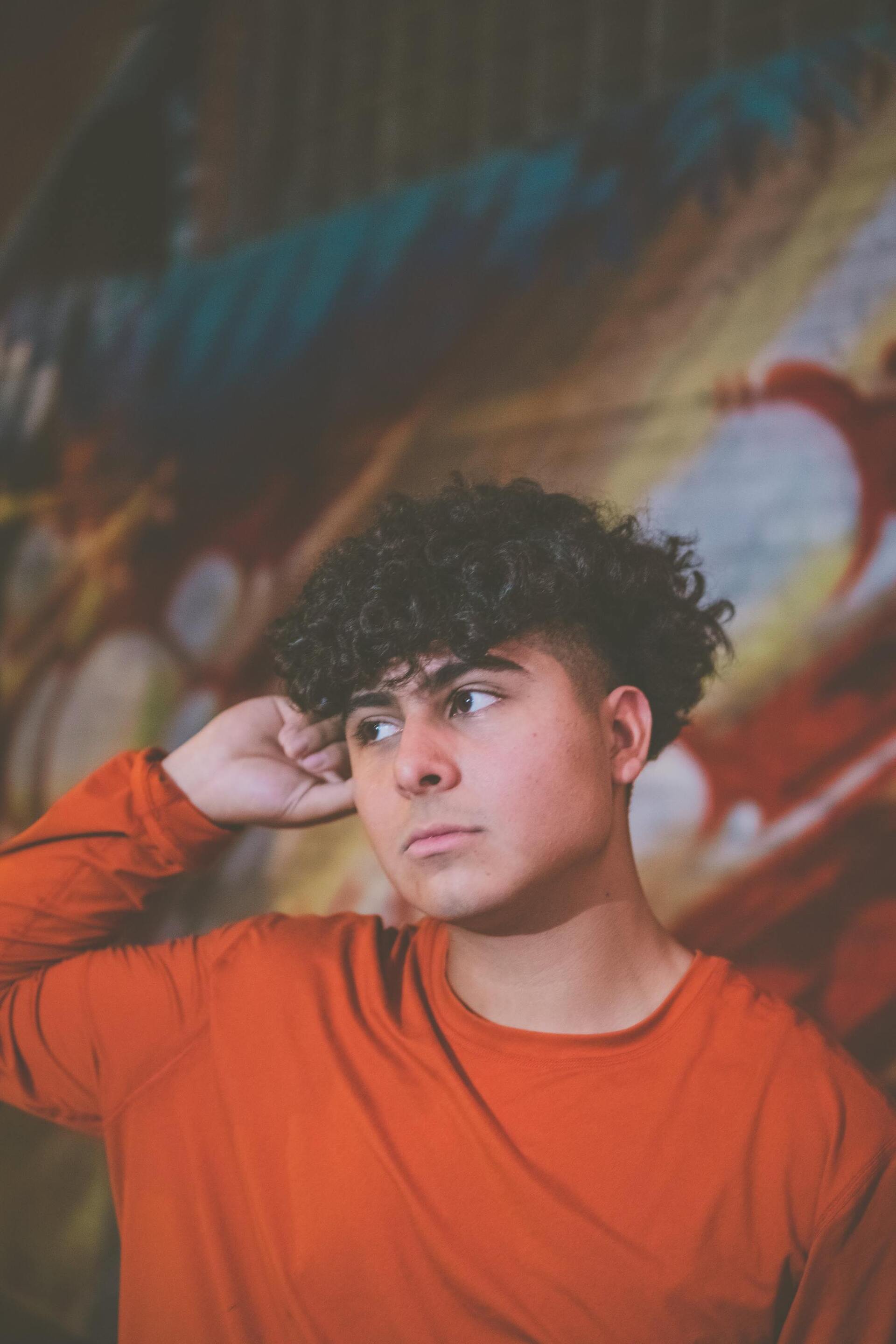 man perm: man with short dark curly hair with a curly fringe and undercuts