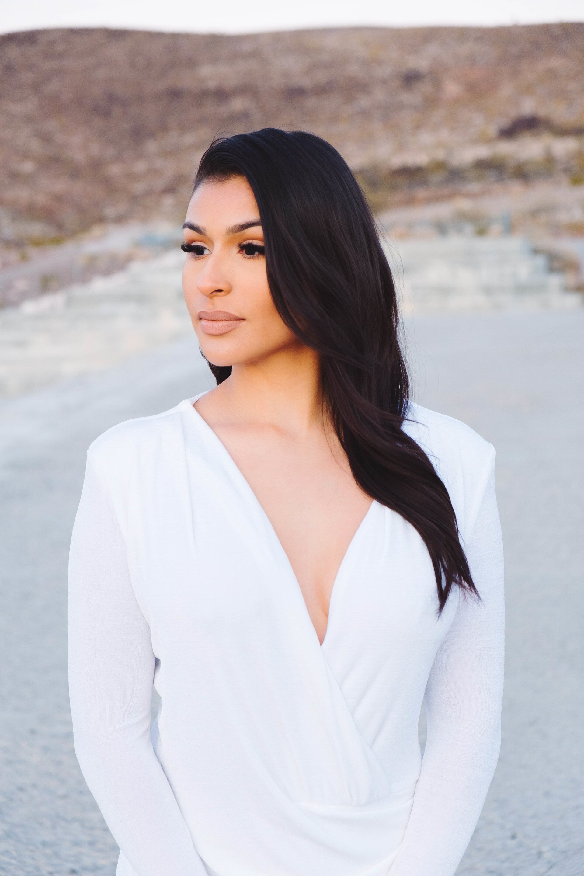 NYE hairstyles: woman with sleek wavy hair swept over one shoulder