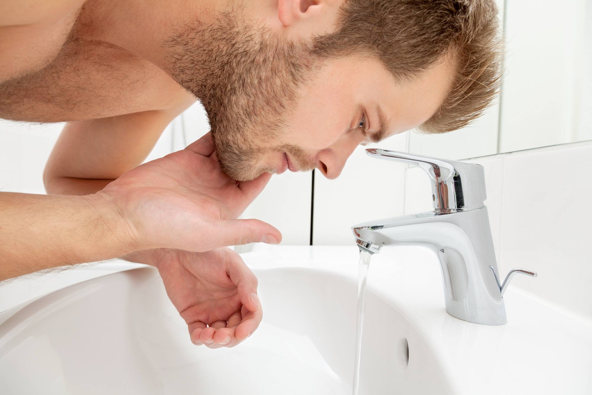 beard care: man splashing water onto his beard