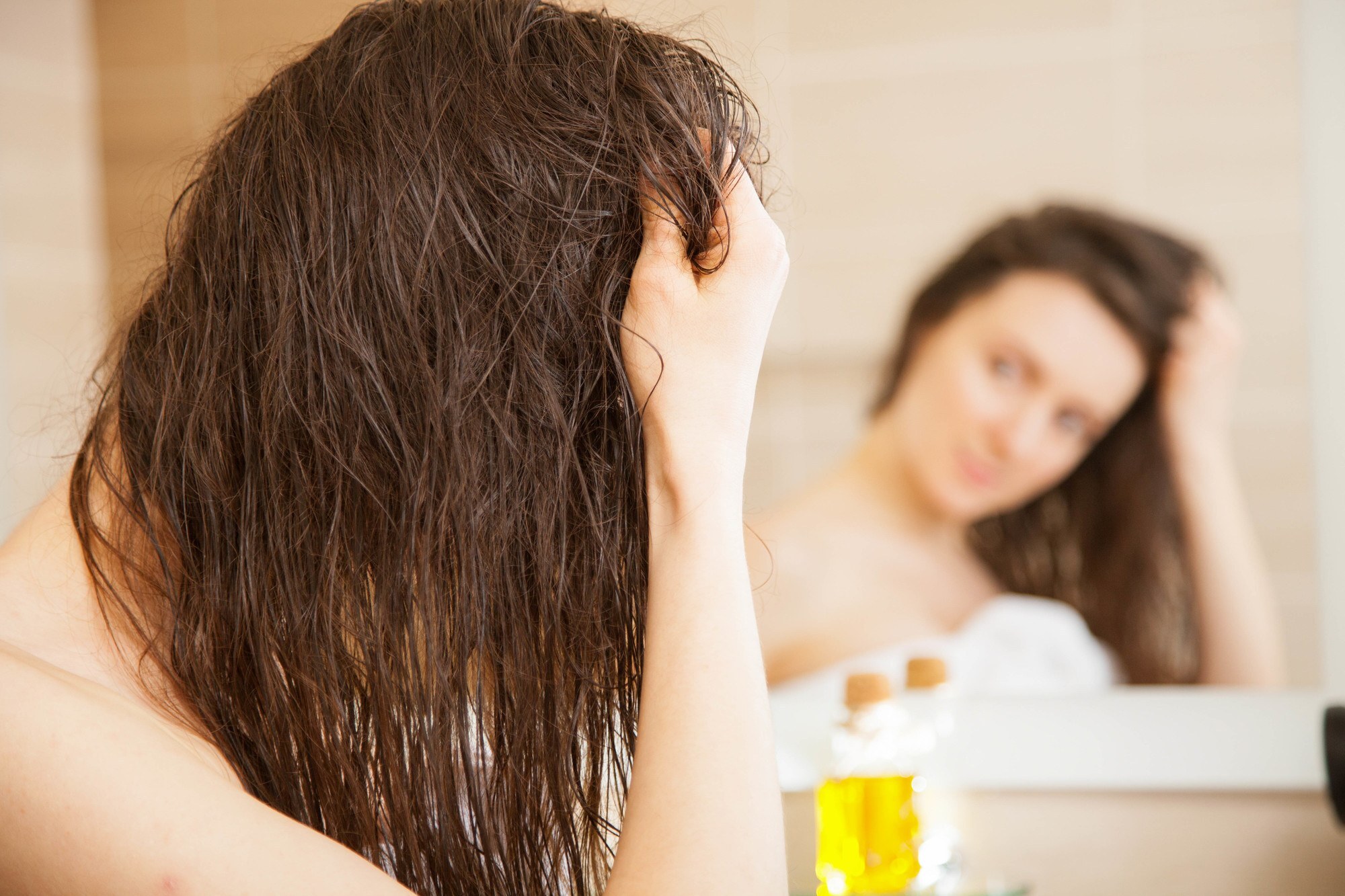 moisturise your hair: woman applying castor oil to her dark brown hair