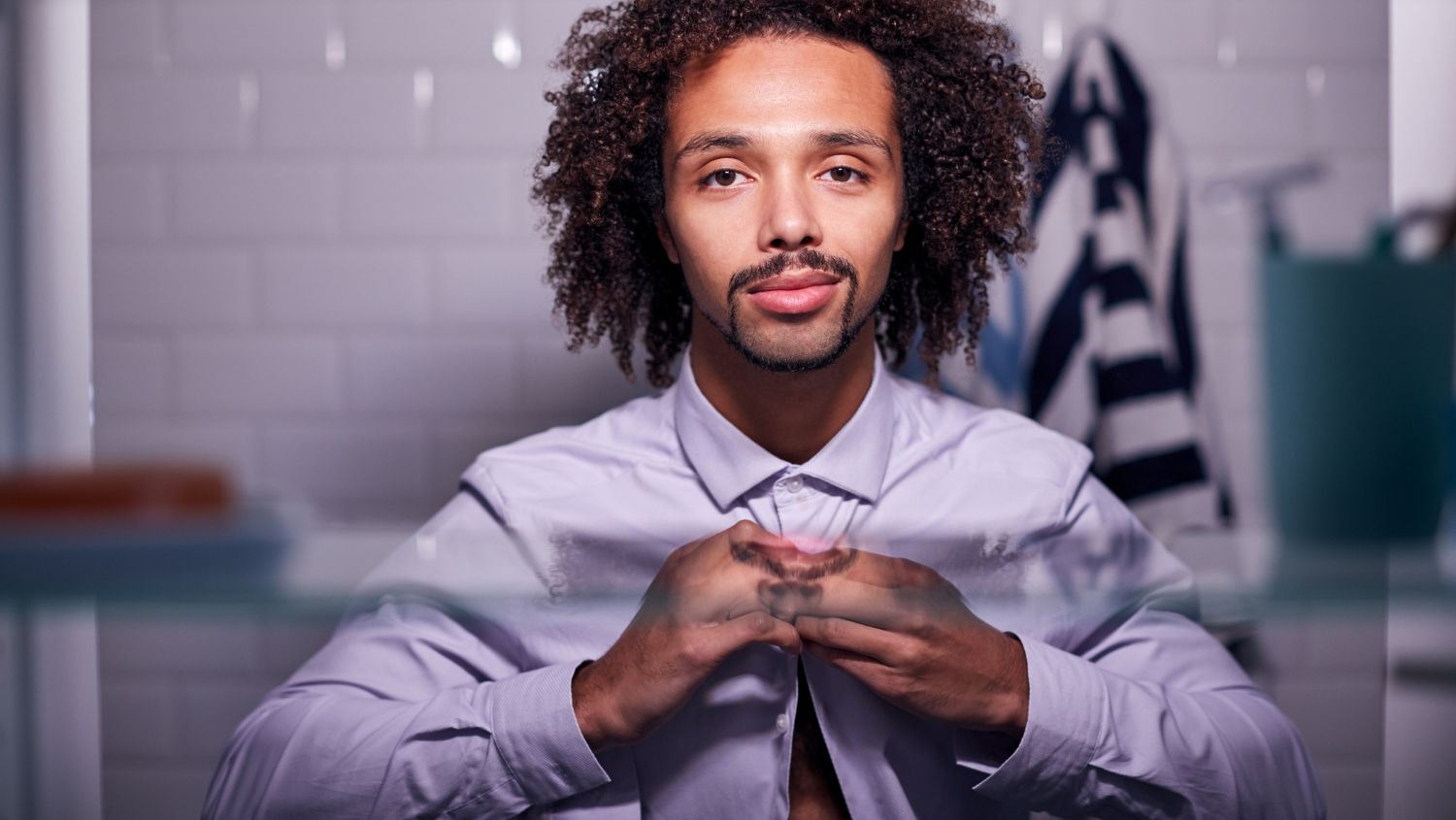 Man getting dressed while looking in the bathroom mirror with no sign of body odor