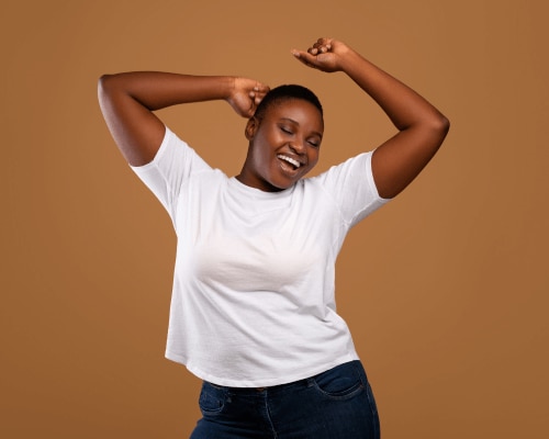 Smiling young woman with her arms raised