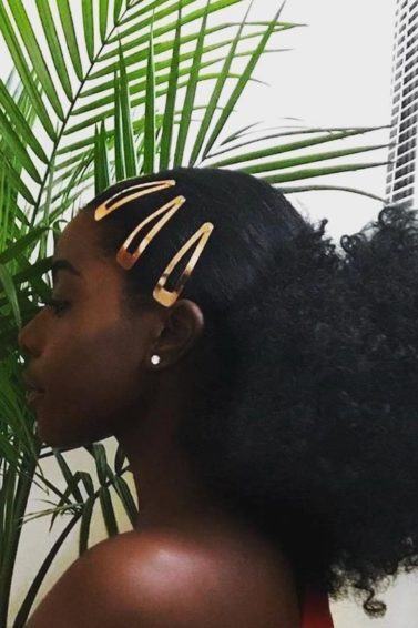 Mulher com cabelos afro rabo de cavalo e franja presa com tic-tacs