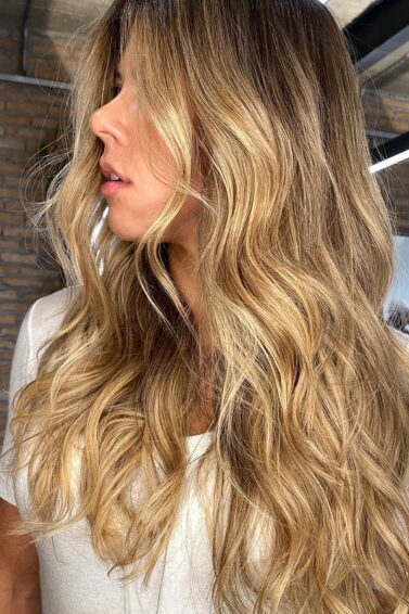 Mulher de blusa clara e cabelo com luzes mel