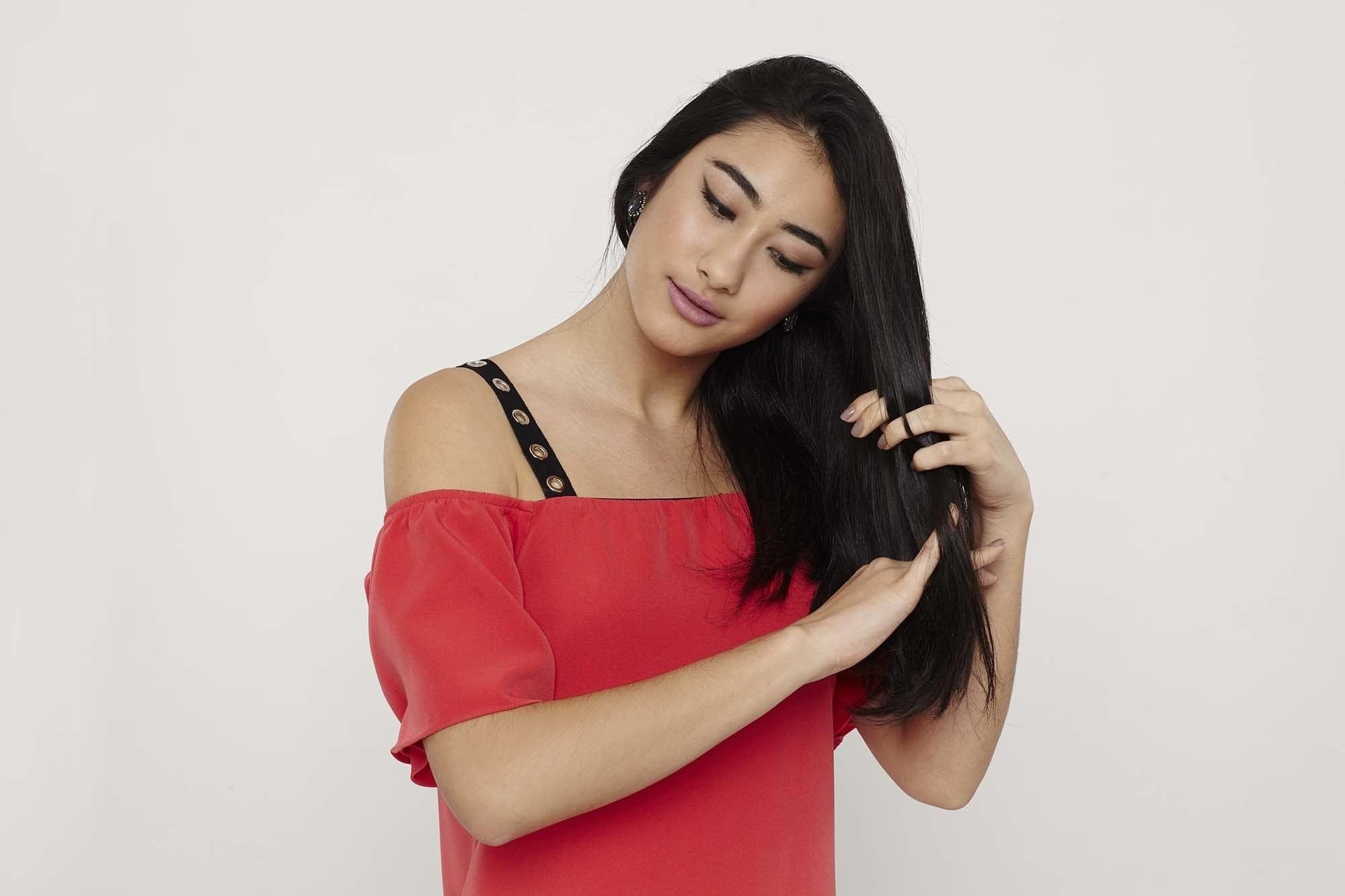 Modelo com cabelo preto liso e blusa rosa ombro a ombro