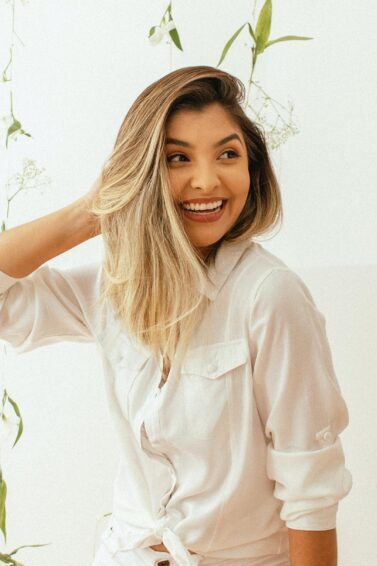 mulher loira sorrindo mexendo no cabelo