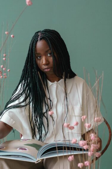mulher com box braids sentada segurando livro