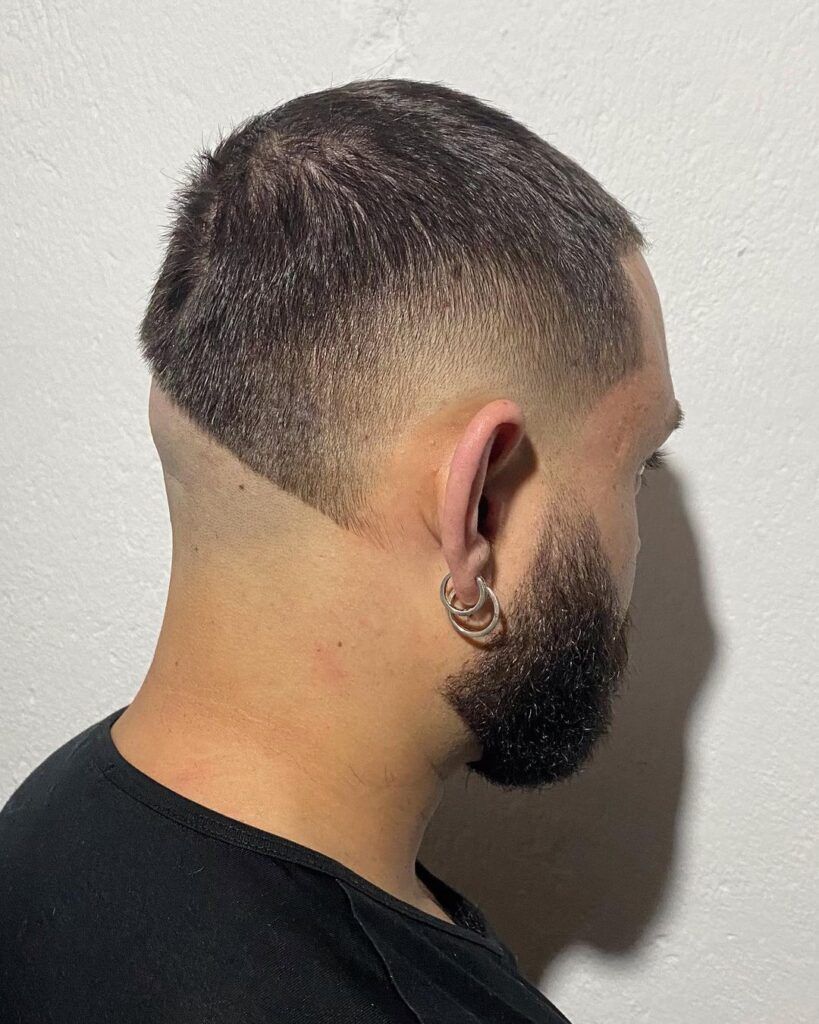 Homem de costas com camiseta preta e corte mullet raspado no cabelo