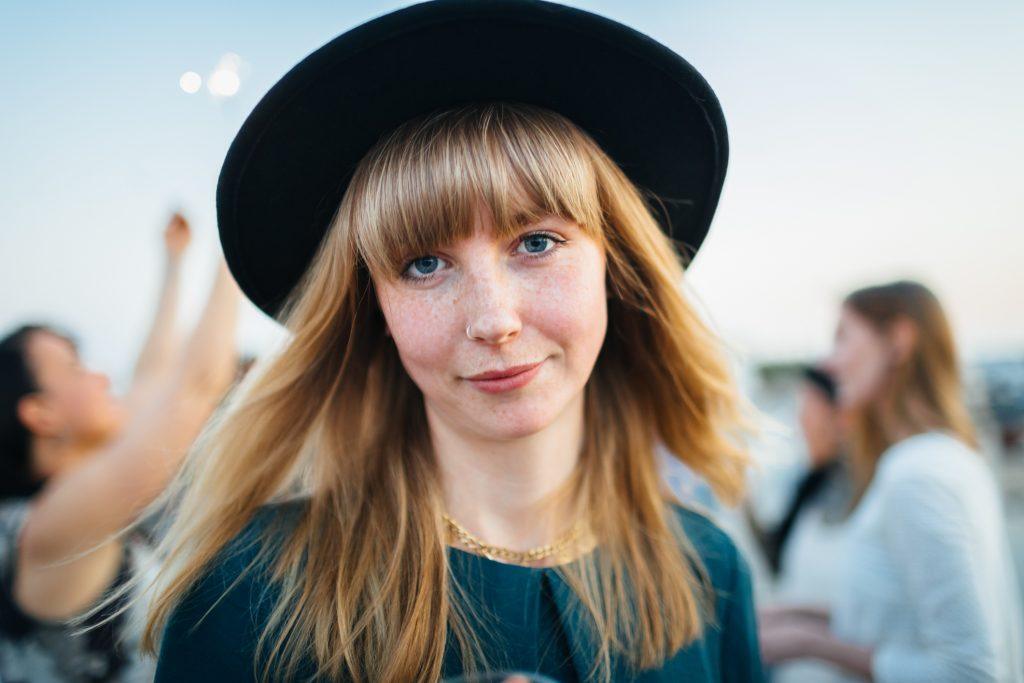 mulher loira com cabelo longo, franja e chapeu