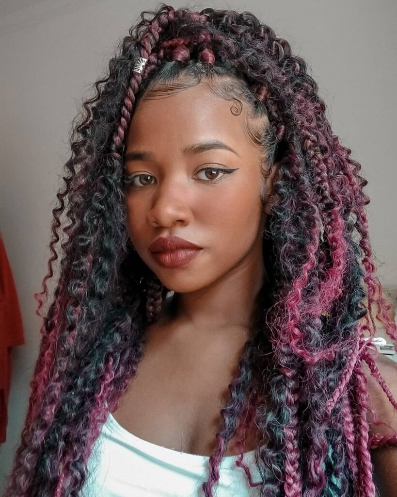 Mulher posa de blusa branca e cabelo com tranças goddess braids no cabelo preto e marsala
