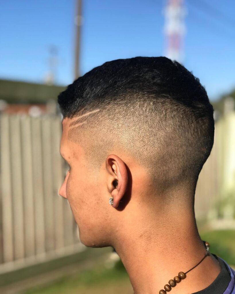 Homem de perfil ao ar livre com corte high fade com listra no cabelo