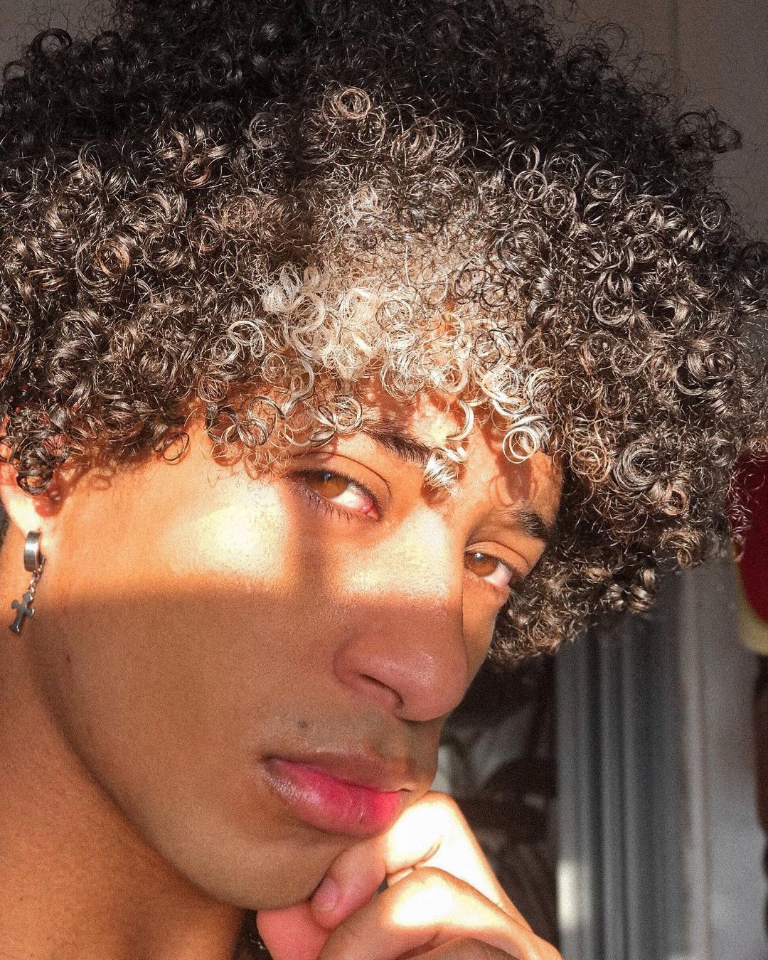 homem com cabelo cacheado 3C e mecha branca