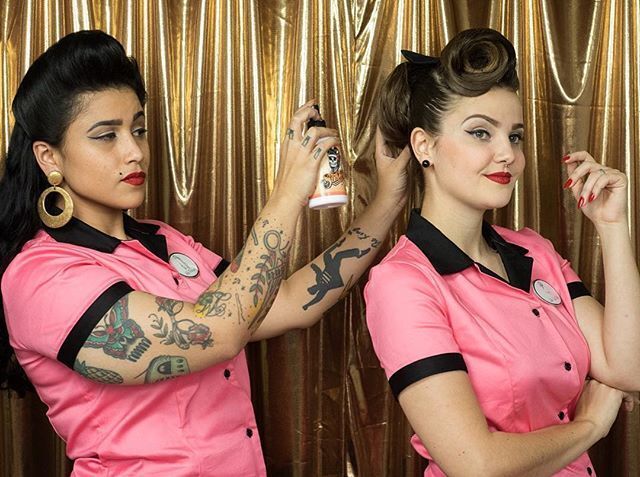 Mulher de camisa rosa e estilo vintage arruma o cabelo de outra jovem de camisa rosa