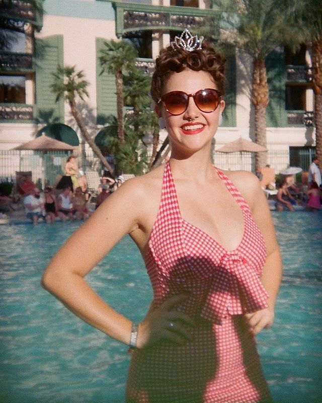 Mulher posa com vestido xadrez vichy e óculos escuros em frente a piscina