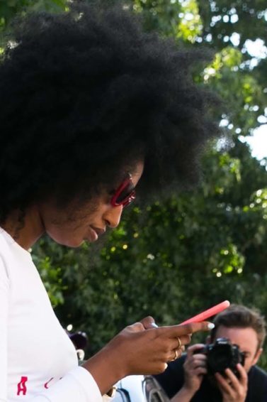 Mulher usa cabelo black power, blusa branca e saia amarela. Ela ilustra matéria sobre como fazer o Cabelo crespo mais solto