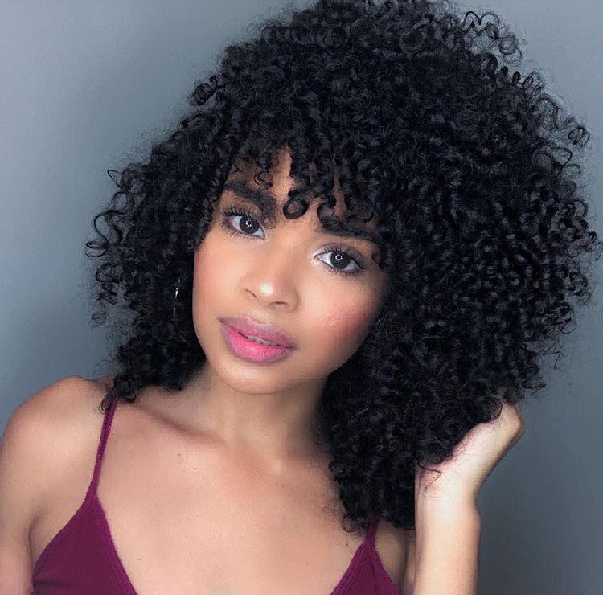 mulher com cabelo médio cacheado e franja
