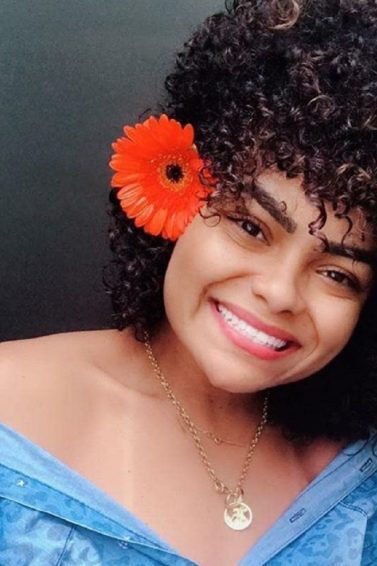 mulher de cabelo com permanente afro com flor