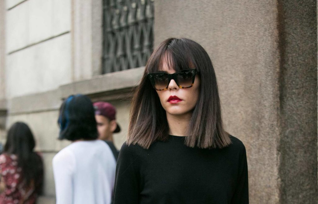 mulher usa blusa preta, oculos escuro e cabelo com blunt cut