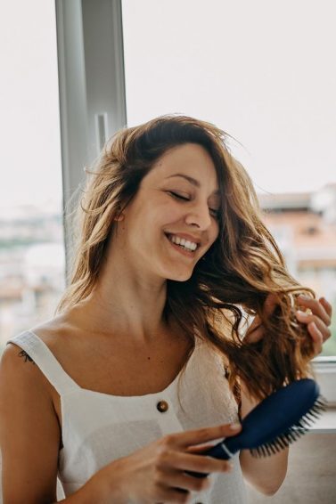 mulher penteando o cabelo depois de usar o kit cronograma capilar