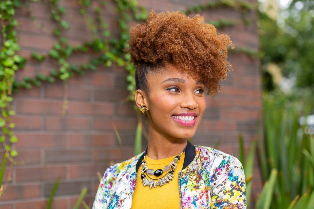 Mulher com cabelo crespo e coque abacaxi, penteado ideal para amarrar o cabelo antes de dormir