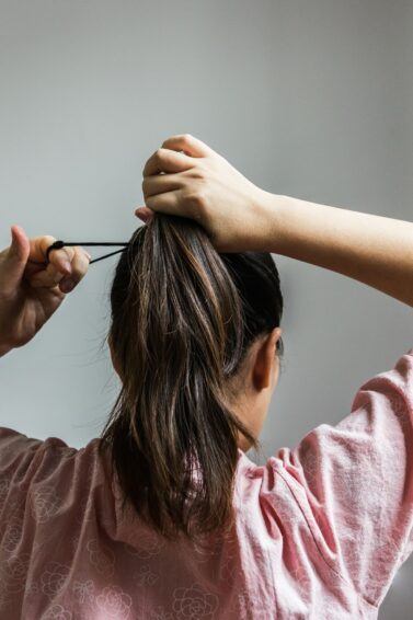 mulher de costas prendendo o cabelo