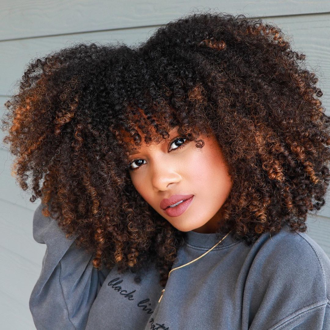 Mulher com cabelo cacheado e luzes