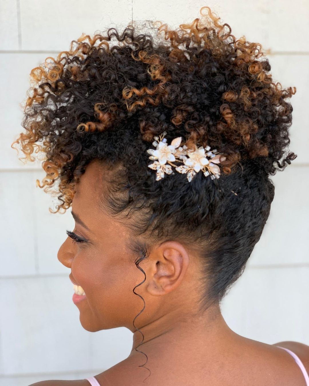 Mulher com cabelo preso em um coque e mechas californianas nas pontas