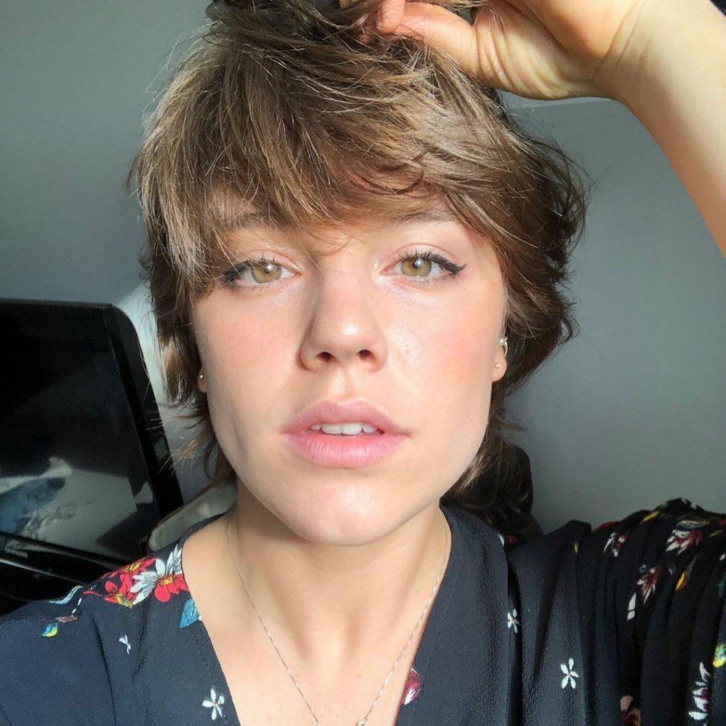 mulher com cabelo curto loiro escuro com franja