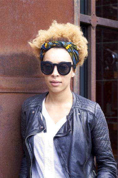 Mulher com cabelo afro loiro posa, usando bandana
