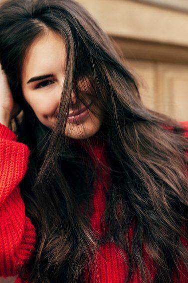 mulher mexendo no cabelo longo de blusa vermelha